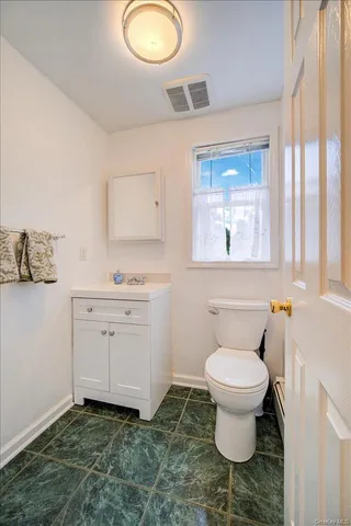 a bathroom with a granite countertop toilet a sink and a mirror