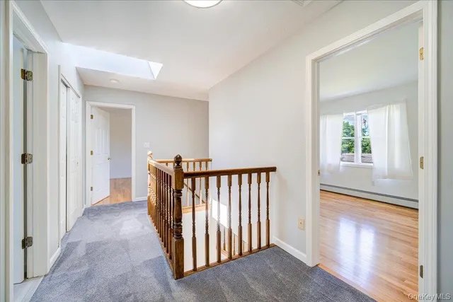 a view of a hallway with wooden floor and a bathroom