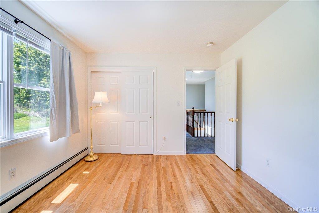11 Catskill Avenue Monroe, NY 10950 - Photo 38 of 48 Unfurnished bedroom featuring a baseboard radiator, light wood-style flooring, baseboards, and a closet