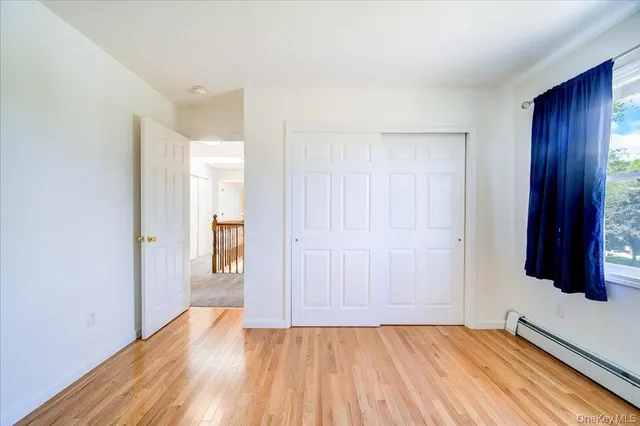 a view of an empty room with wooden floor and a bathroom
