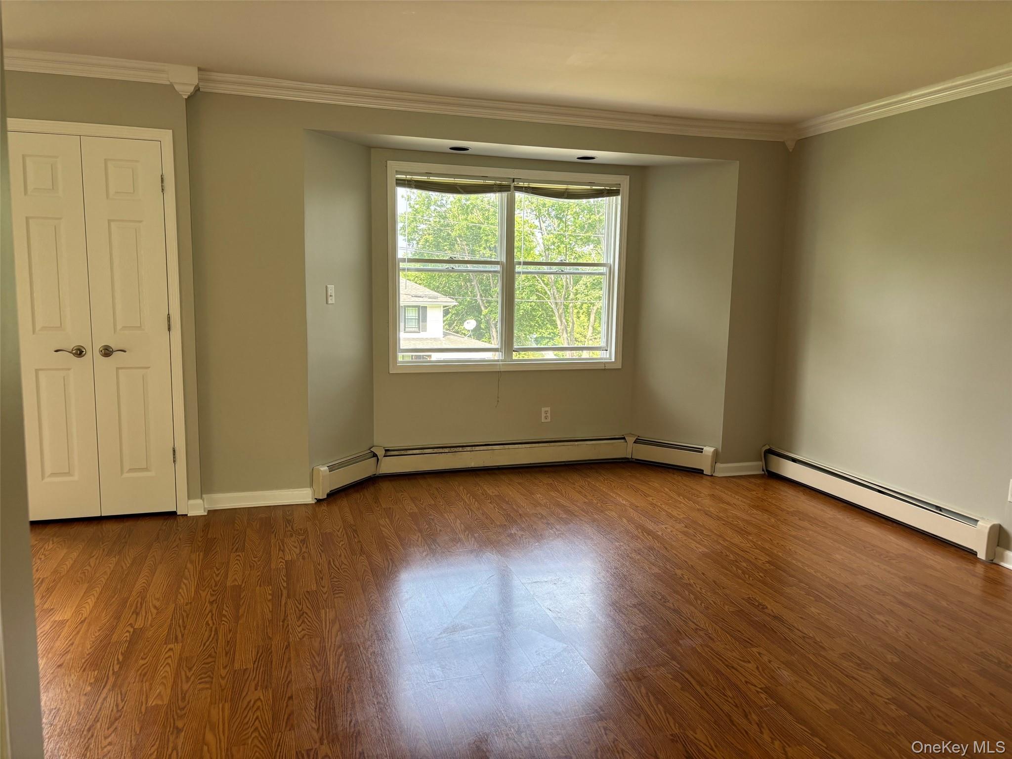 11 Catskill Avenue Monroe, NY 10950 - Photo 6 of 48 Unfurnished room featuring a baseboard heating unit, crown molding, and wood finished floors