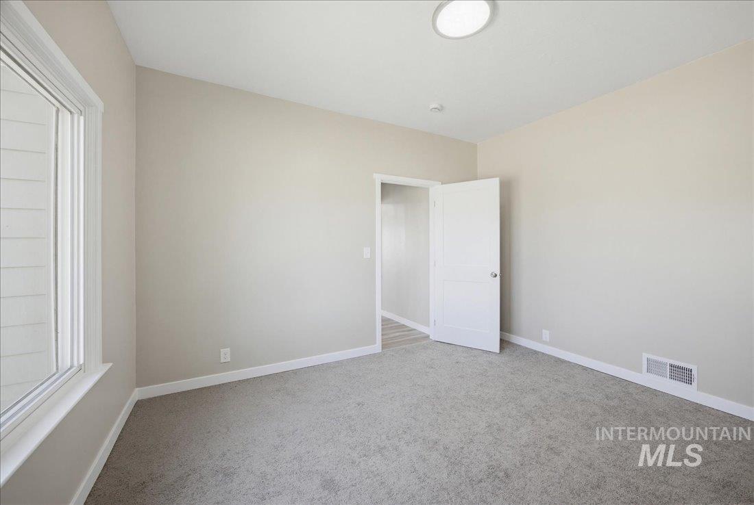 30013 Apple Valley Road Parma, ID 83660 - Photo 17 of 25 Carpeted room featuring a large window, neutral wall tones, white trim, and a contemporary ceiling light fixture