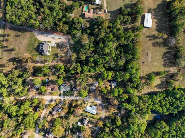 an aerial view of residential house with outdoor space and trees all around
