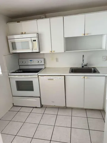 a kitchen with granite countertop white cabinets and appliances