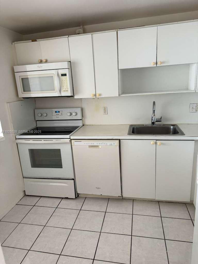 13499 Biscayne Boulevard, Unit 1404 North Miami, FL 33181 - Photo 4 of 13 a kitchen with granite countertop white cabinets and appliances