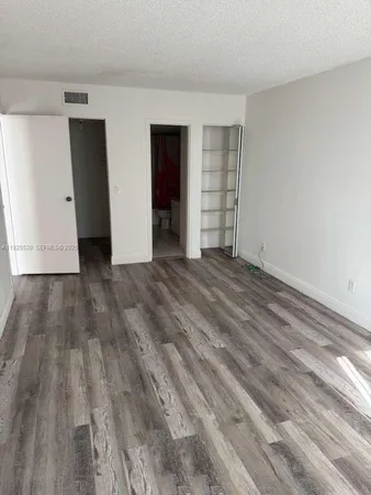 a view of an empty room with closet and kitchen