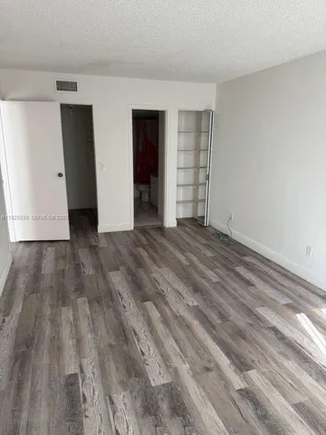 a view of an empty room with closet and kitchen