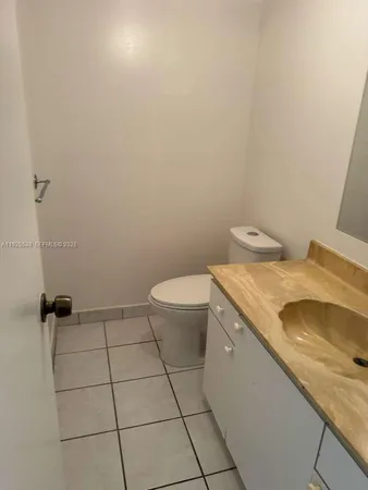 a bathroom with a granite countertop sink and a toilet
