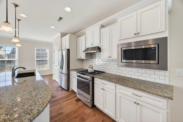 a kitchen with stainless steel appliances granite countertop a stove a sink and a microwave