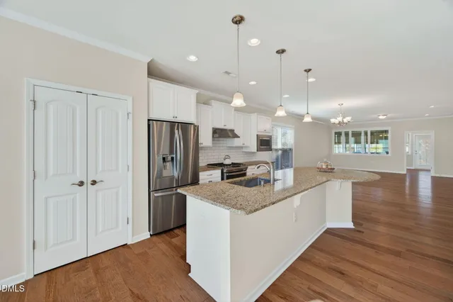 a kitchen with stainless steel appliances granite countertop a refrigerator a oven and a wooden floors