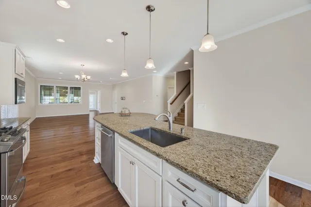 a kitchen with stainless steel appliances granite countertop a sink a oven and wooden floor
