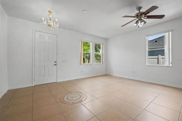an empty room with windows and ceiling fan