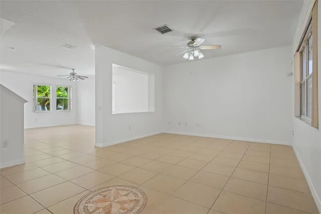 a view of an empty room with a chandelier fan and a window