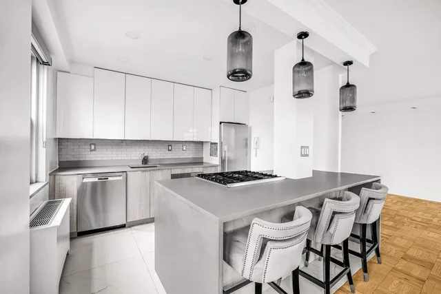 a kitchen with stainless steel appliances granite countertop a sink a stove a refrigerator and white cabinets with wooden floor