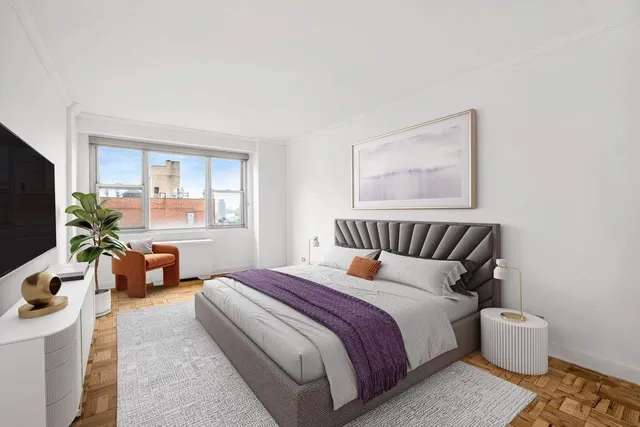 a bedroom with a bed a couch and a flat tv screen on the dresser