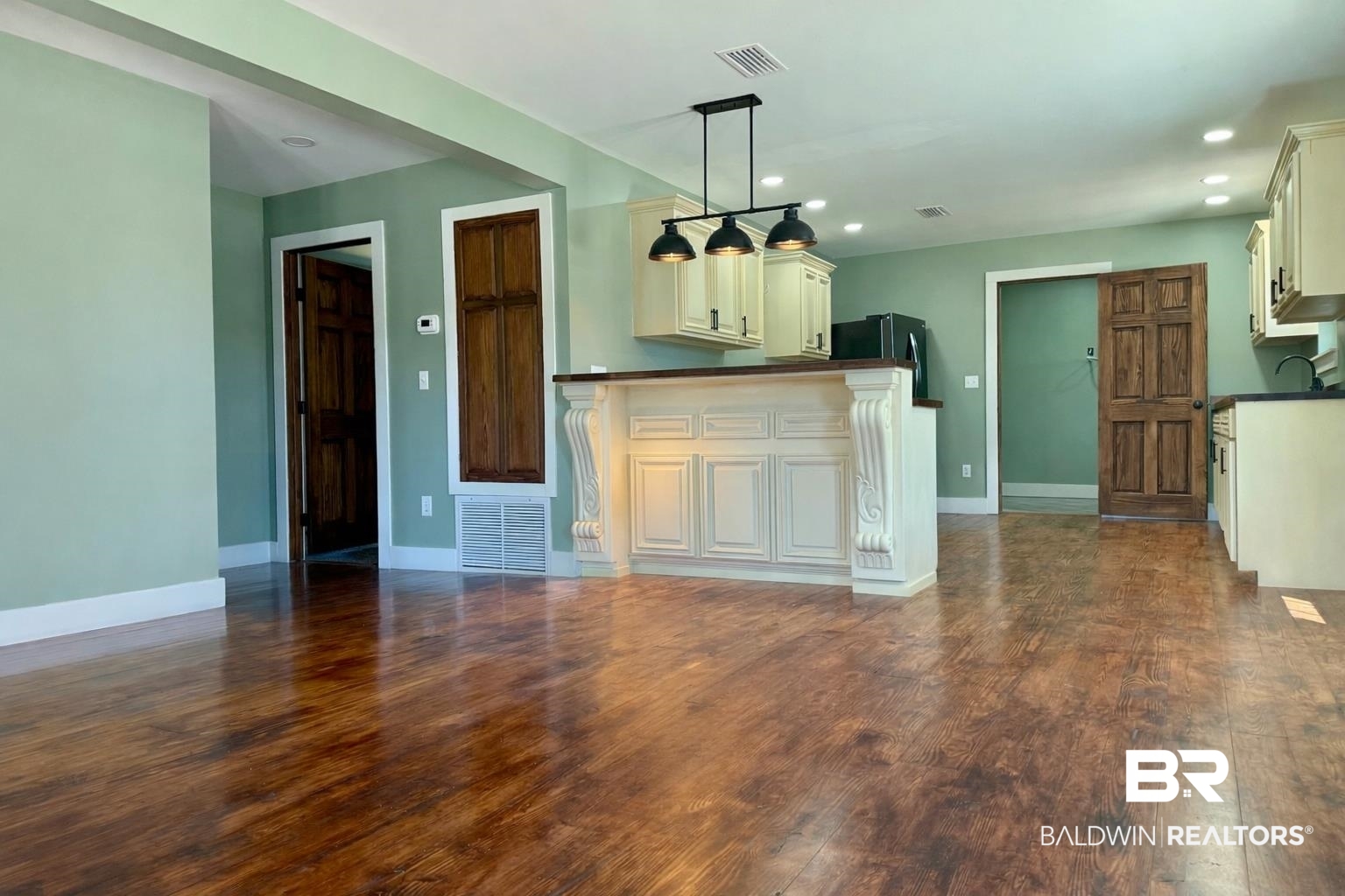 613 Forrest Avenue Brewton, AL 36426 - Photo 7 of 22 Kitchen featuring dark countertops, dark wood finished floors, hanging light fixtures, freestanding refrigerator, and white cabinetry