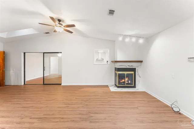 a view of an empty room with window and wooden floor