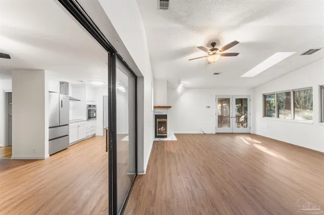 a view of an empty room with window and wooden floor