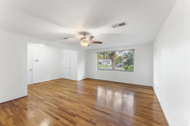a view of an empty room with wooden floor and a window