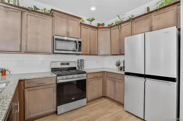 a kitchen with granite countertop a refrigerator stove and microwave