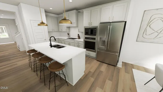 a kitchen with stainless steel appliances a refrigerator a sink a stove and white cabinets with wooden floor