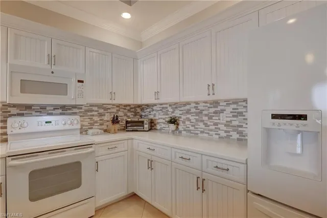 a kitchen with white cabinets and white appliances