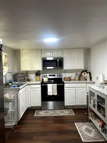 a kitchen with granite countertop a sink cabinets and stainless steel appliances
