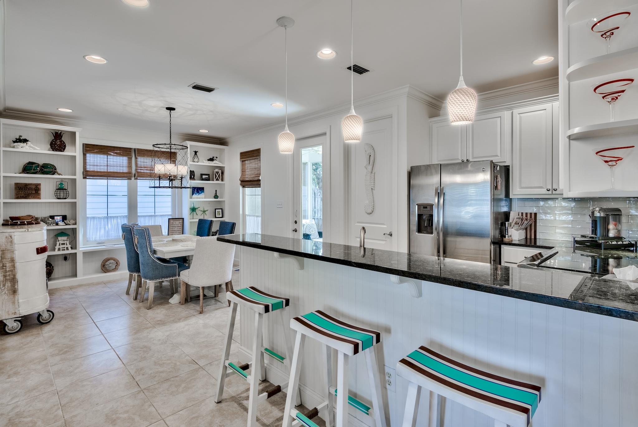 171 South Zander Way Santa Rosa Beach, FL 32459 - Photo 14 of 32 a kitchen with stainless steel appliances kitchen island granite countertop a refrigerator a sink a stove and chairs with wooden floor