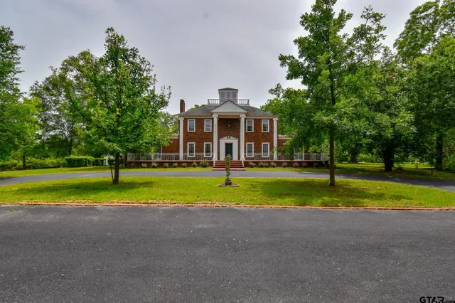 a view of a house with a big yard and large trees