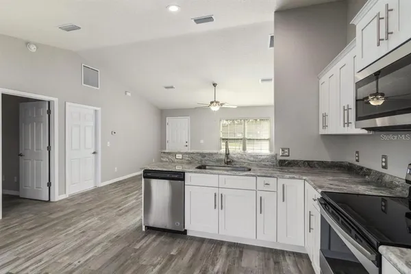 a kitchen with stainless steel appliances granite countertop a sink and cabinets with wooden floor