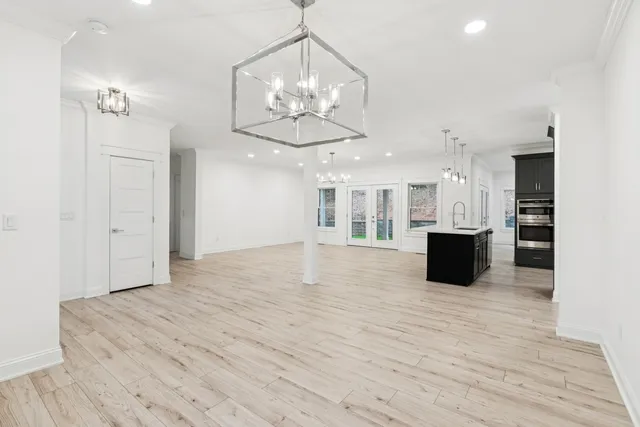 a view of an empty room and kitchen with wooden floor