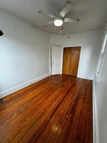 a view of empty room with wooden floor and fan
