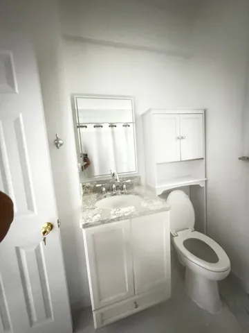 a bathroom with a granite countertop toilet sink and mirror