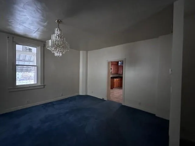 a view of an empty room with chandelier and a window