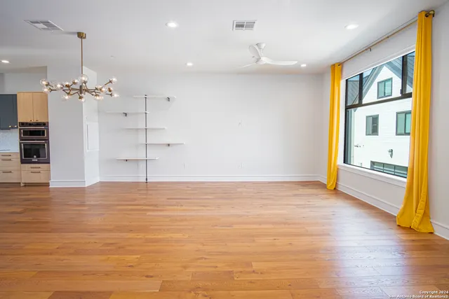 a view of an empty room with a window and wooden floor