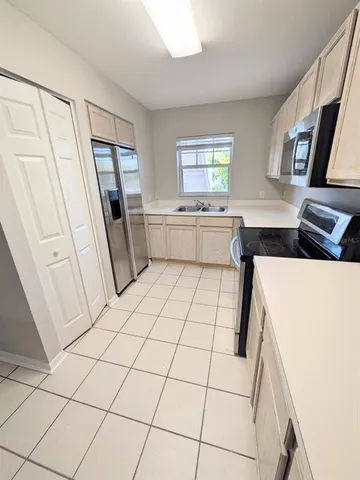 a kitchen with a sink a refrigerator a window and white cabinets
