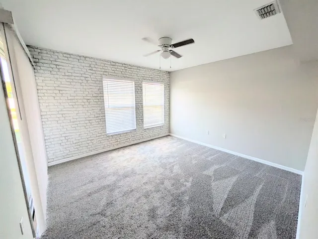 an empty room with windows and ceiling fan