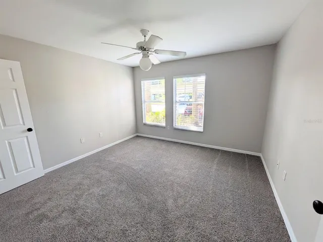 an empty room with windows and fan