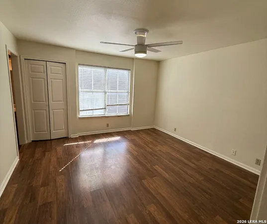 an empty room with wooden floor cabinet and windows