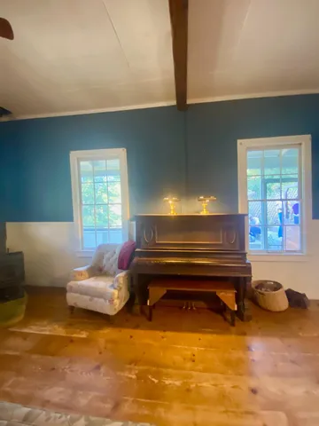 a living room with furniture a dining table and a piano next to a large window