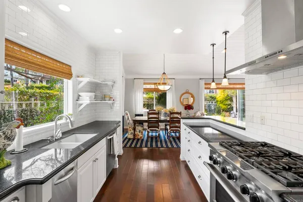 a kitchen with stainless steel appliances granite countertop a stove and a view of living room