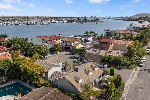an aerial view of a city with lots of residential buildings and ocean view in back