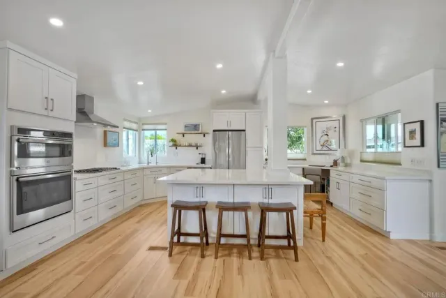 a kitchen with stainless steel appliances kitchen island granite countertop a table chairs sink and cabinets