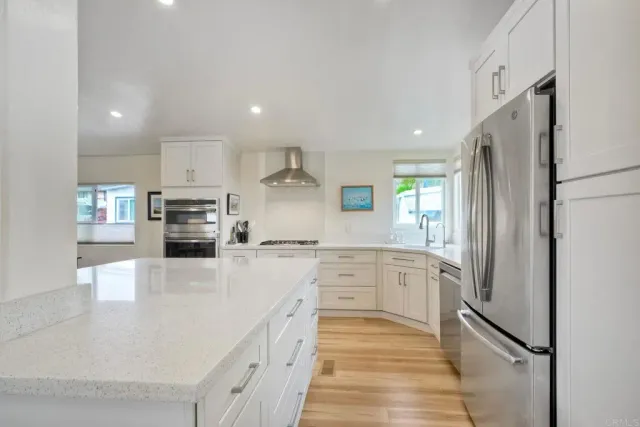 a large kitchen with stainless steel appliances granite countertop a refrigerator and a sink