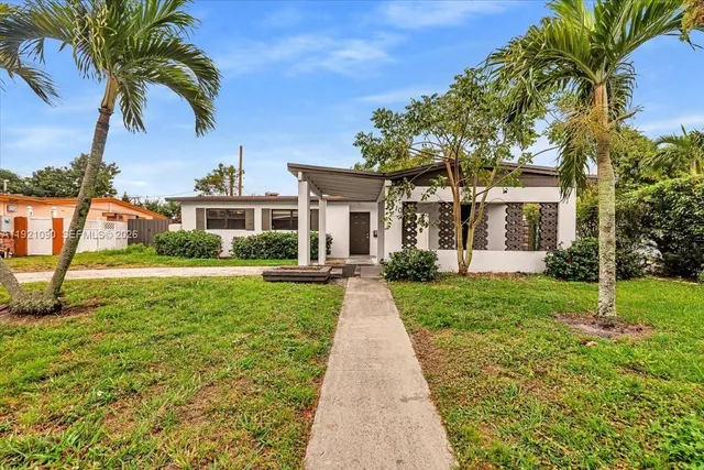 a front view of a house with a yard and potted plants