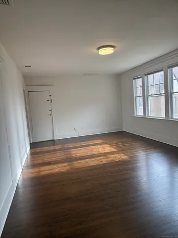 an empty room with wooden floor and windows with curtains
