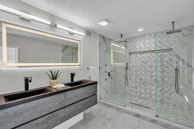 a bathroom with a granite countertop sink a mirror and shower