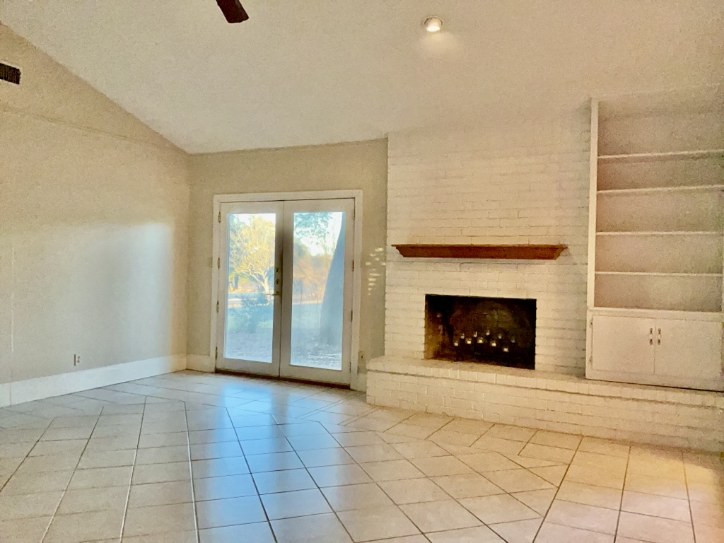 418 Sunset Drive Georgetown, TX 78628 - Photo 5 of 26 Living room with a ceiling fan, a brick fireplace, lofted ceiling, light tile patterned flooring, and french doors
