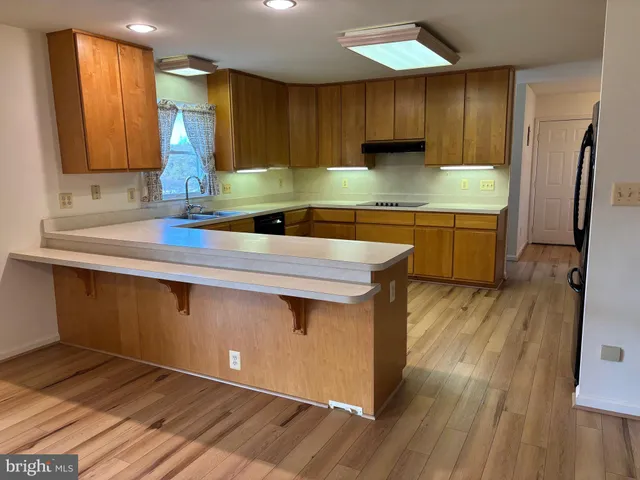 a kitchen with stainless steel appliances granite countertop a sink a stove a refrigerator cabinets and wooden floor