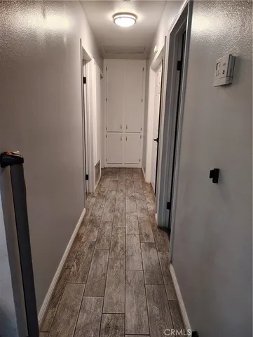 a view of a hallway with wooden floor and a bathroom